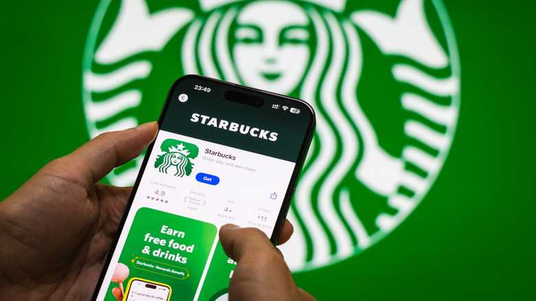 Hand holding a phone open to the Starbucks app