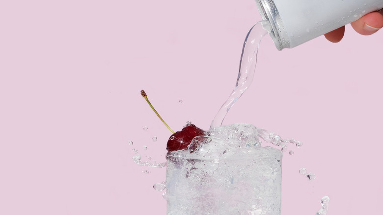 person pouring can into glass