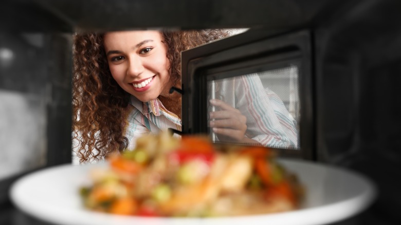 person happily using a microwave