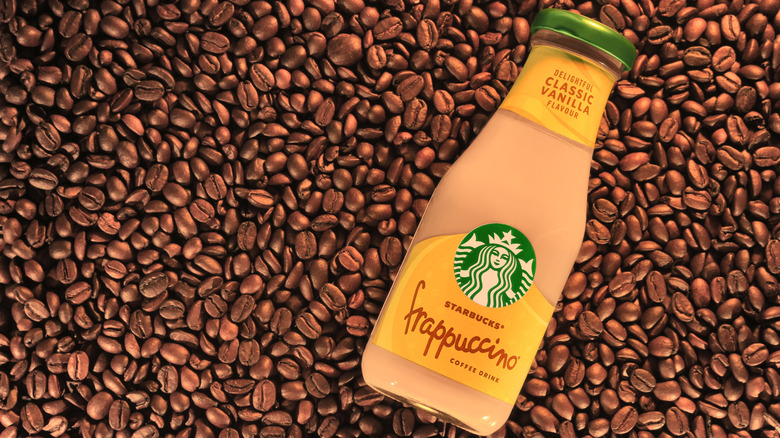 A Starbucks bottled Vanilla Frappuccino drink on coffee beans