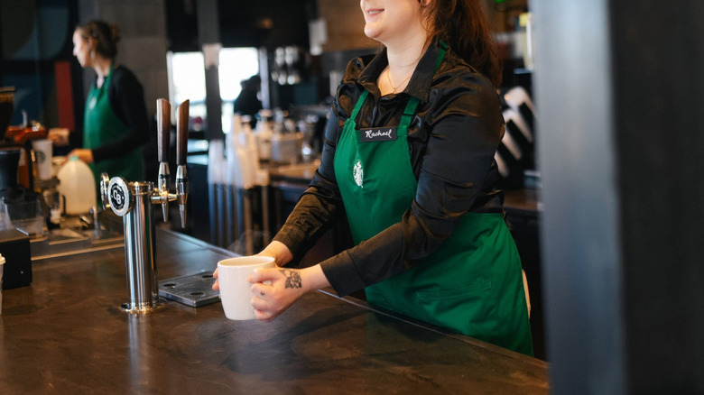 Starbucks employee in black shirt and green apron