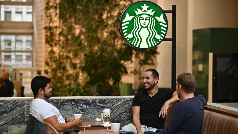 Three men drinking Starbucks coffee