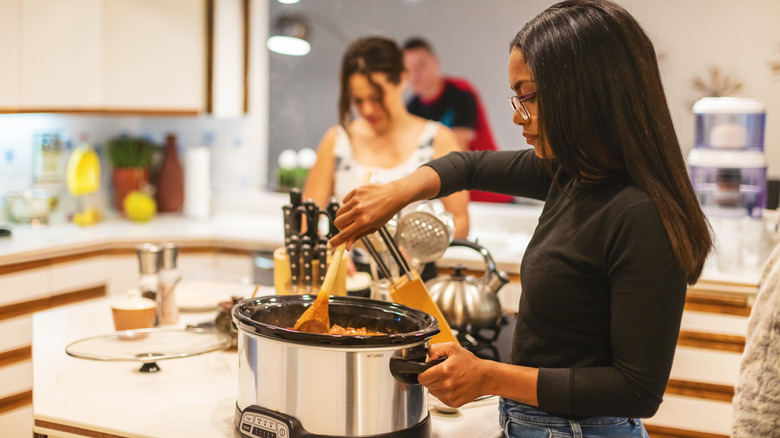 Woman stirring food in slow cooker