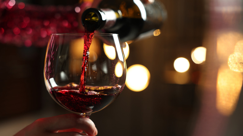 Person pouring a glass of red wine