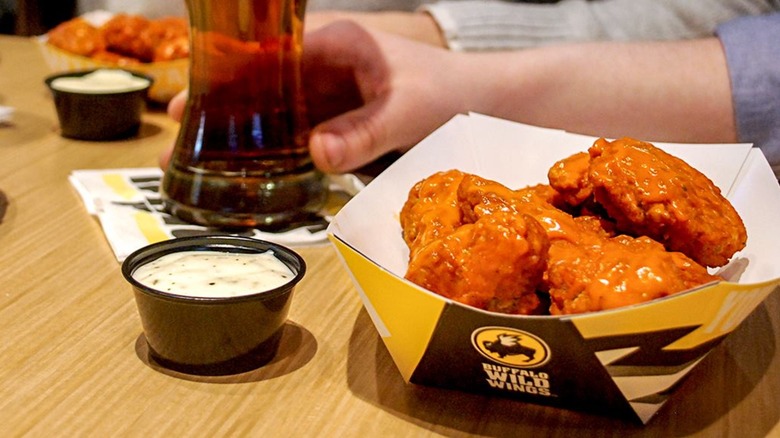 basket of original Buffalo Wild Wings boneless wings with dipping sauce and a beer