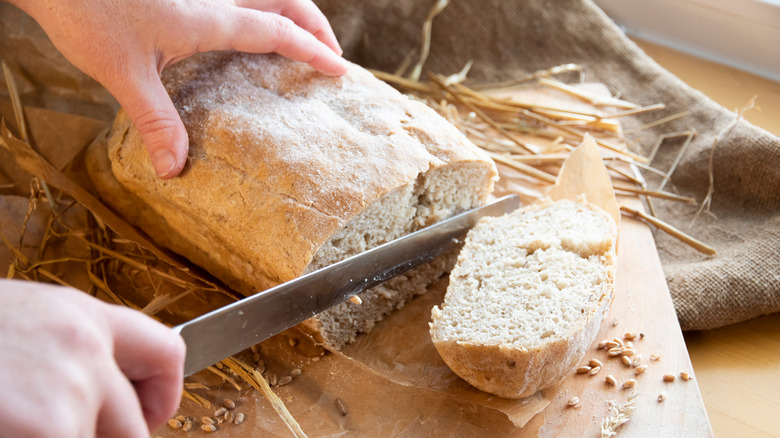 Person slicing loaf of bread