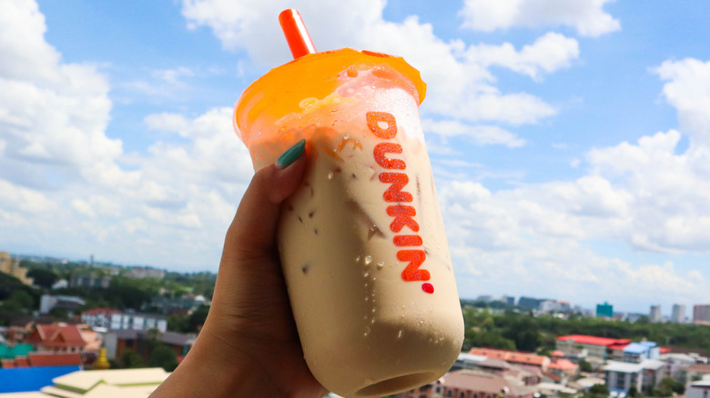 A Dunkin iced coffee held up by a hand