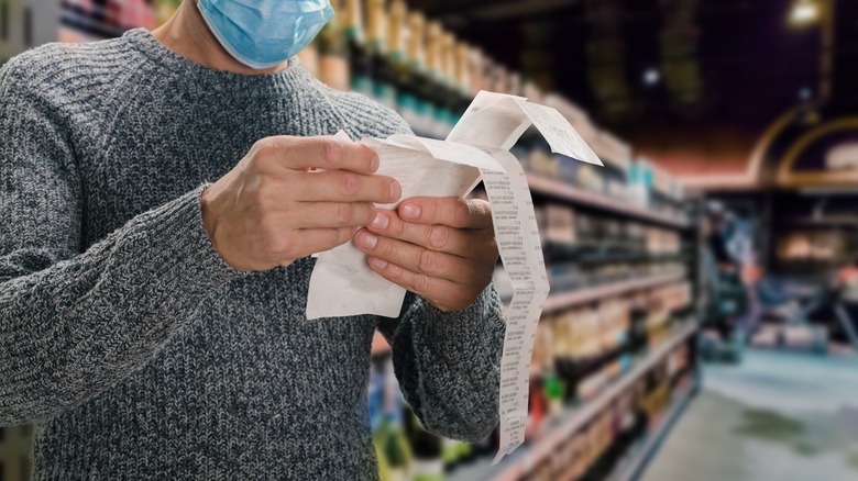 man holding long grocery receipt