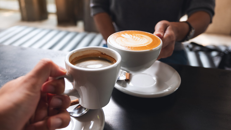 Two people clinking their coffee cups