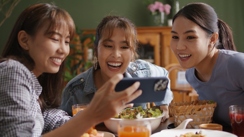 Three people laughing at phone