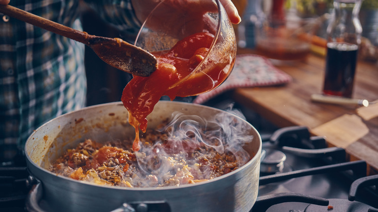 person saucing pasta