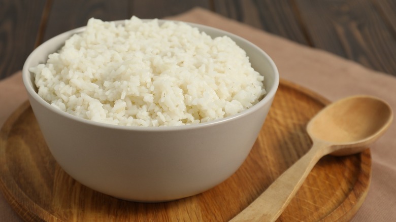 A bowl of white rice with a wooden spoon
