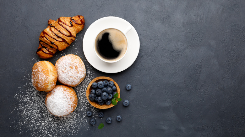 cup of black coffee with baked goods and blueberries