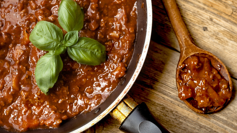 Ragu sauce in pan with basil leaves