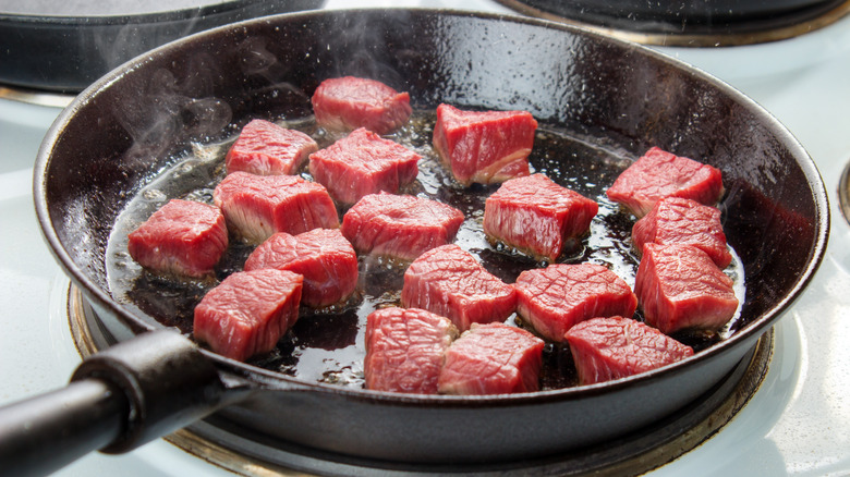 Chunks of beef searing in a pan.