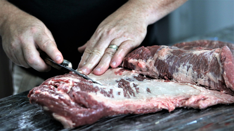 person trimming brisket