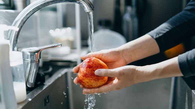 Washing apple under running water