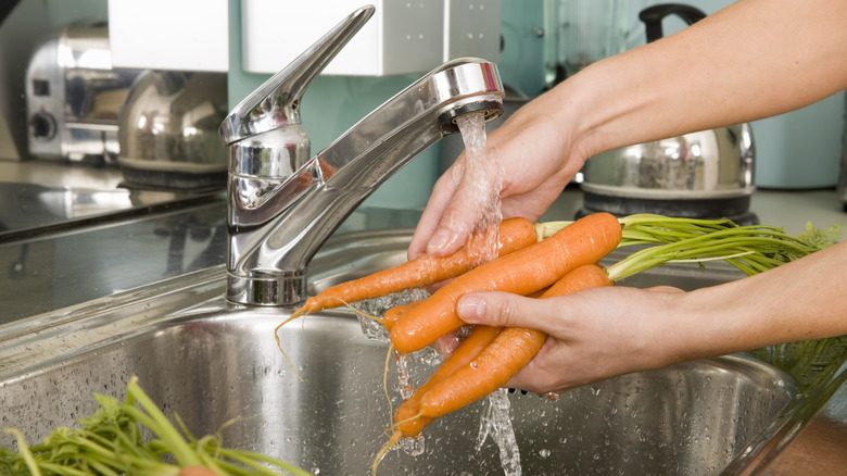 Washing carrots in a sink