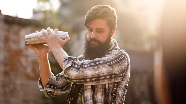 Man holding cocktail shaker near shoulder