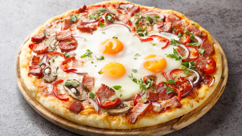 breakfast pizza with bacon, eggs, tomatoes, and scallions