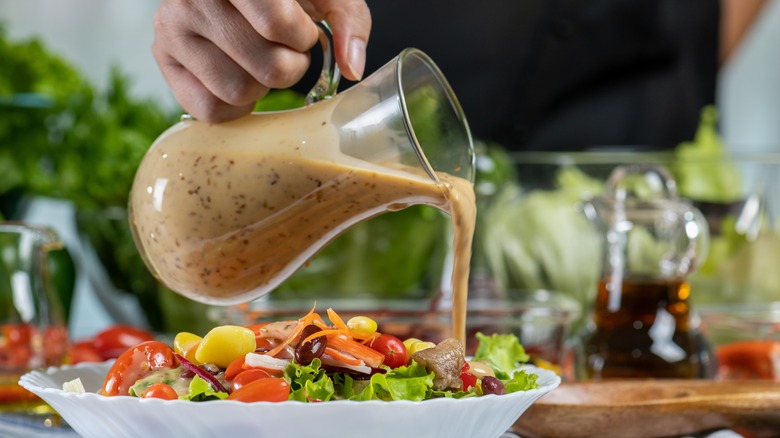 person pouring salad dressing