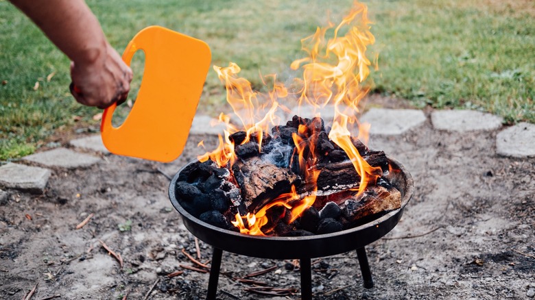 man fanning charcoal grill