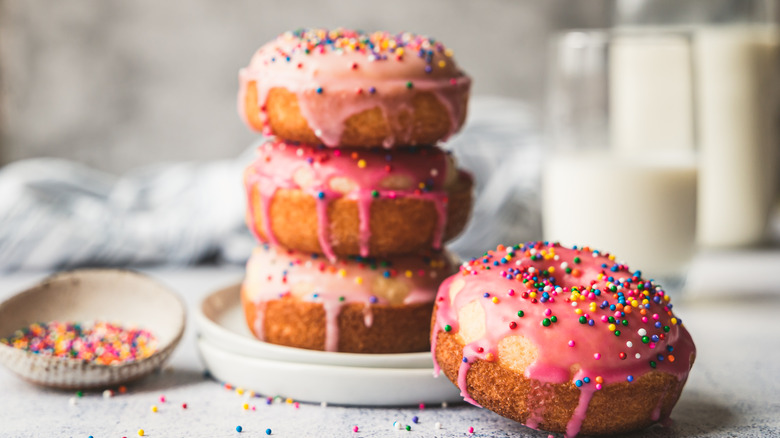 a stack of fresh, homemade donuts with pink icing and sprinkles