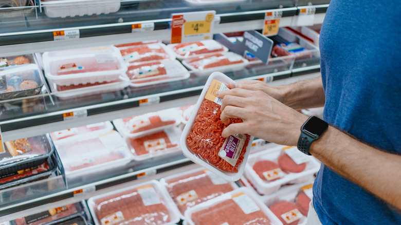 hands holding ground beef package