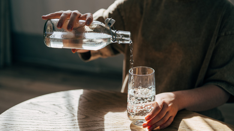 Person pouring water into a glass