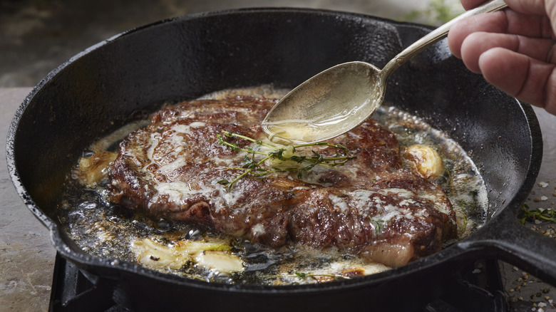 Home cook butter-basting a steak