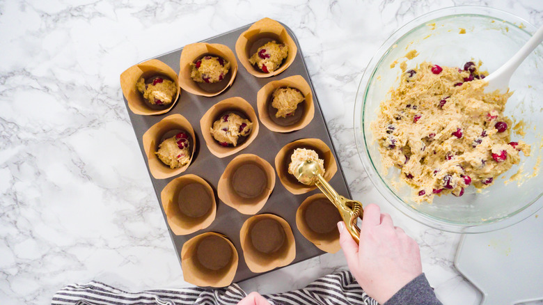 person scooping in muffin mix