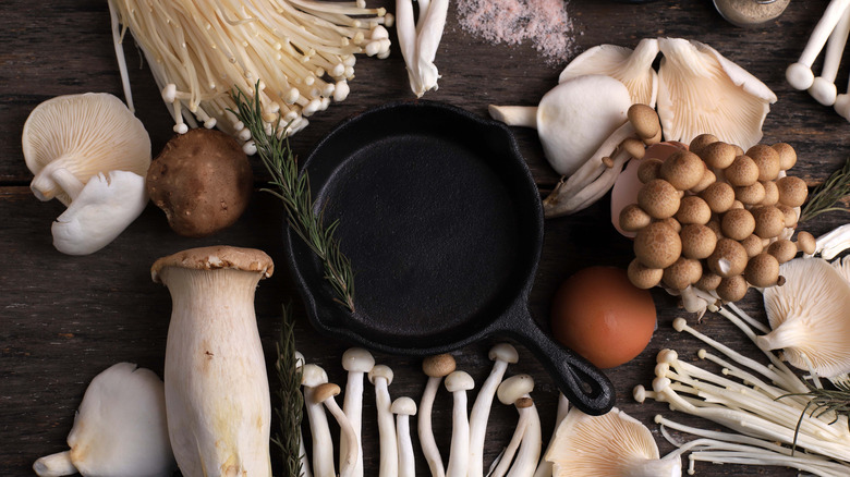 Uncooked mushrooms surrounding a cast iron skillet