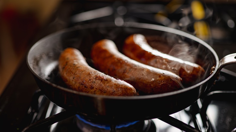 Bratwurst cooking in cast iron skillet