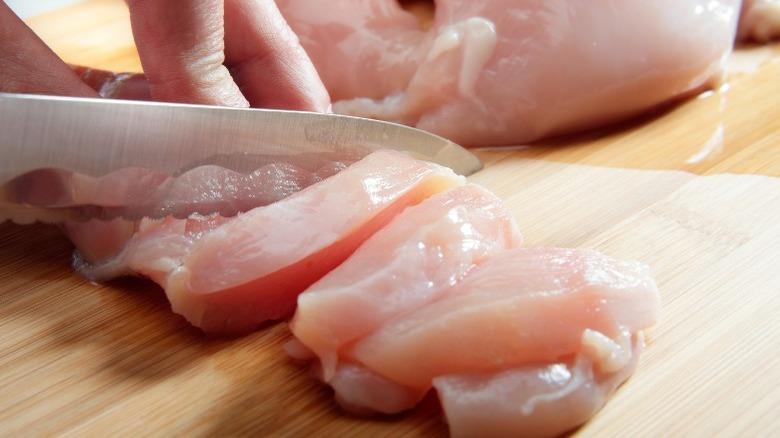 Raw chicken cut on a wooden cutting board