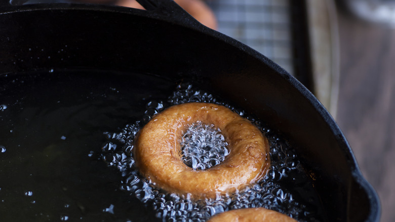 Donuts frying in a cast iron pan