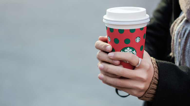 woman holding Starbucks holiday cup