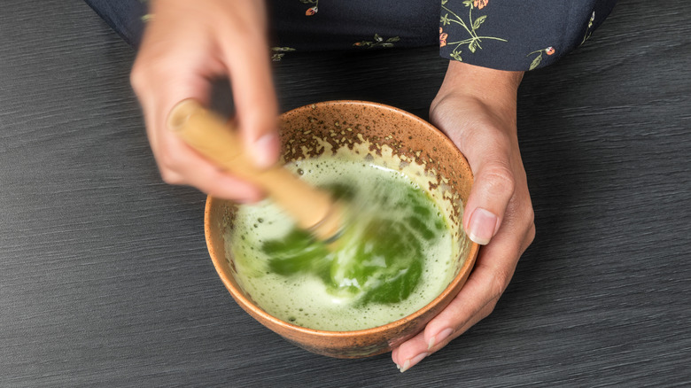 hands whisking matcha with chasen