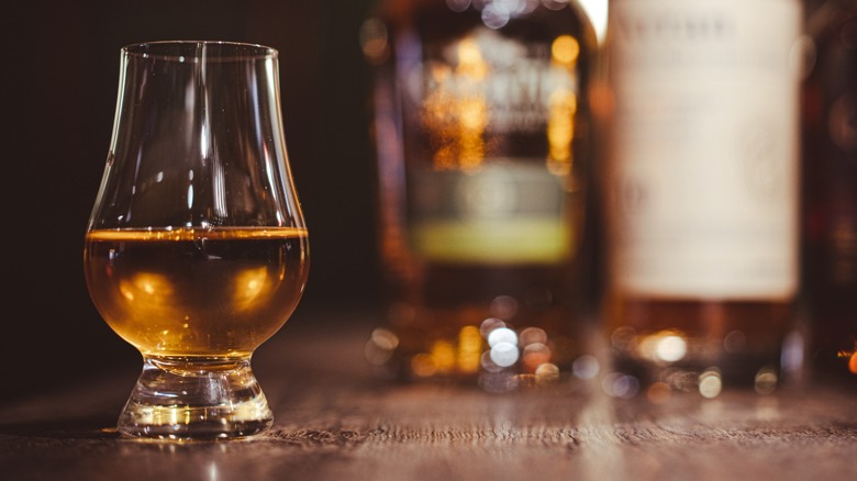 Scotch in a Glencairn glass next to bottles
