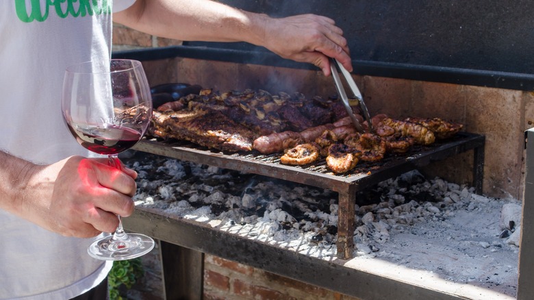 person holding wine while grilling