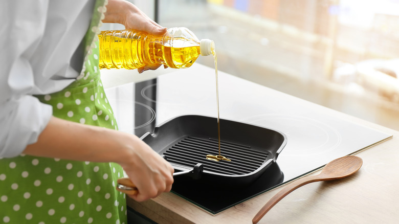 Person pouring oil into a grill pan.