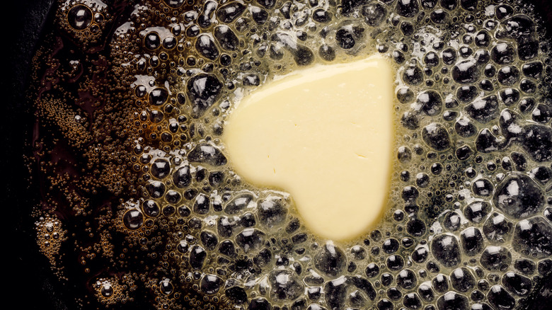 melting heart shaped butter piece in skillet