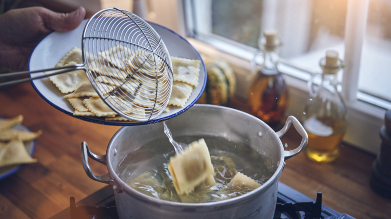 Ravioli in pot and bowl with slotted spoon