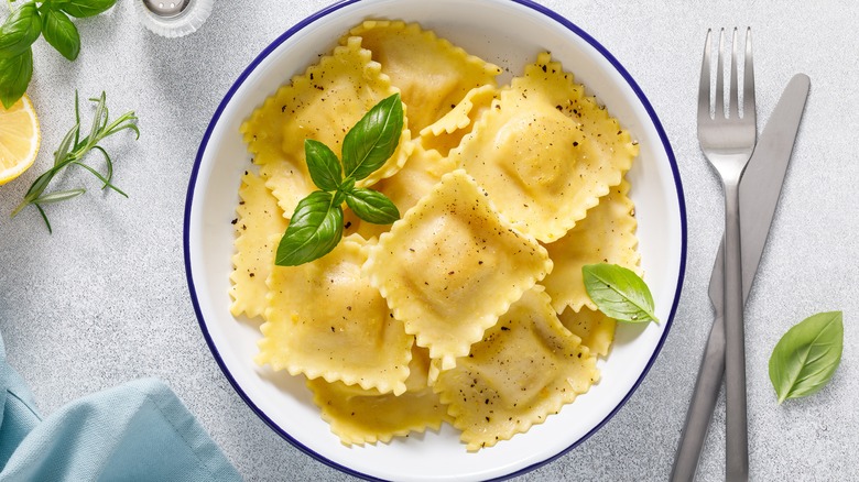 Ravioli in bowl with light sauce, basil