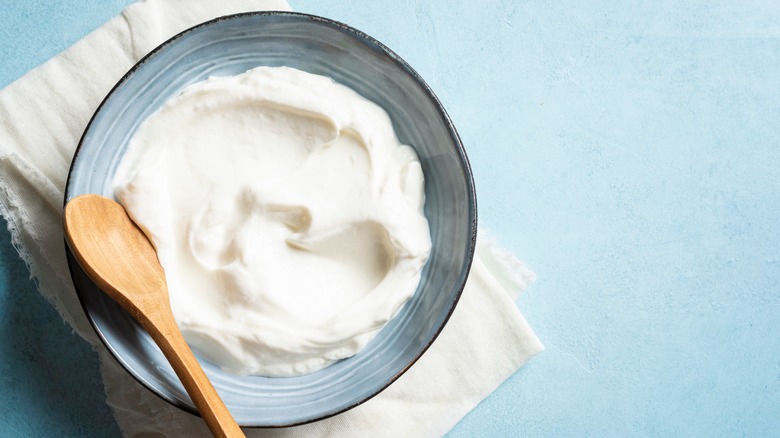 Greek yogurt in a bowl with wooden spoon