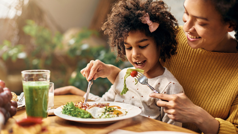 Happy child eating with parent