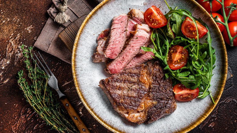 Grilled steak with side salad on rustic table