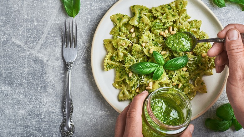 adding pesto to pasta