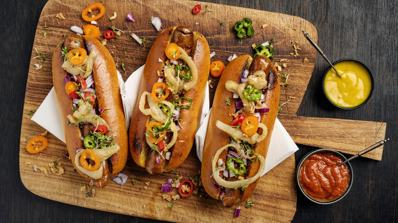 hot dogs with pickles and relish on a wooden board