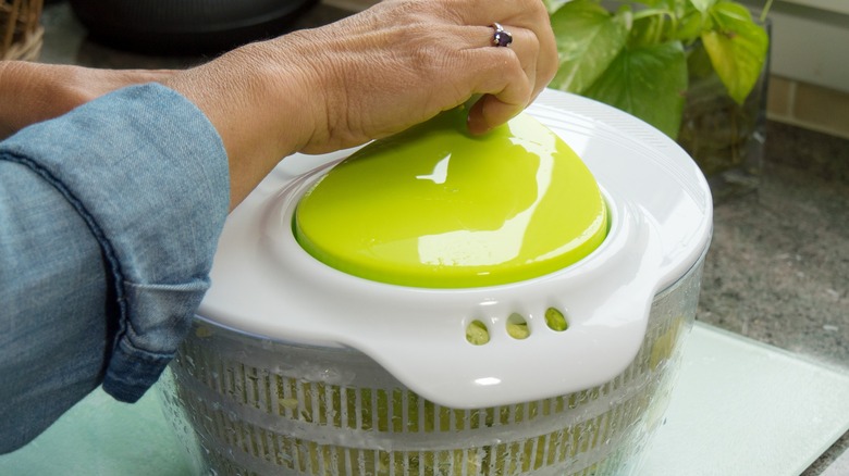 hand of a cook using a salad spinner