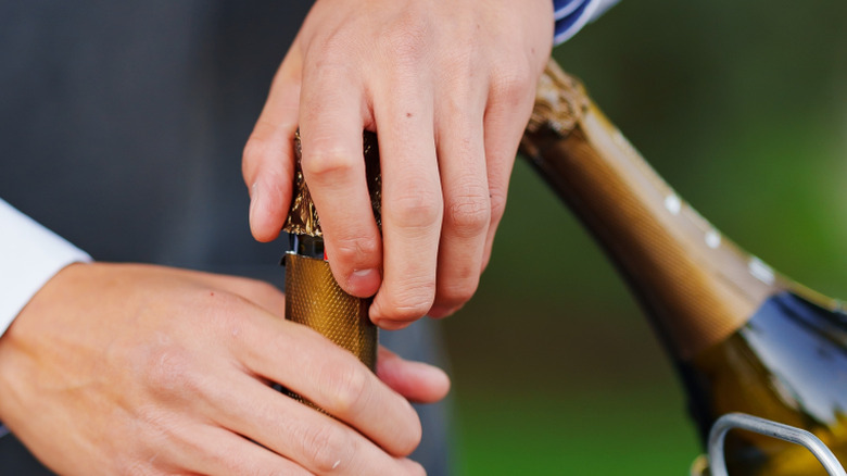 person about to open sparkling wine bottle